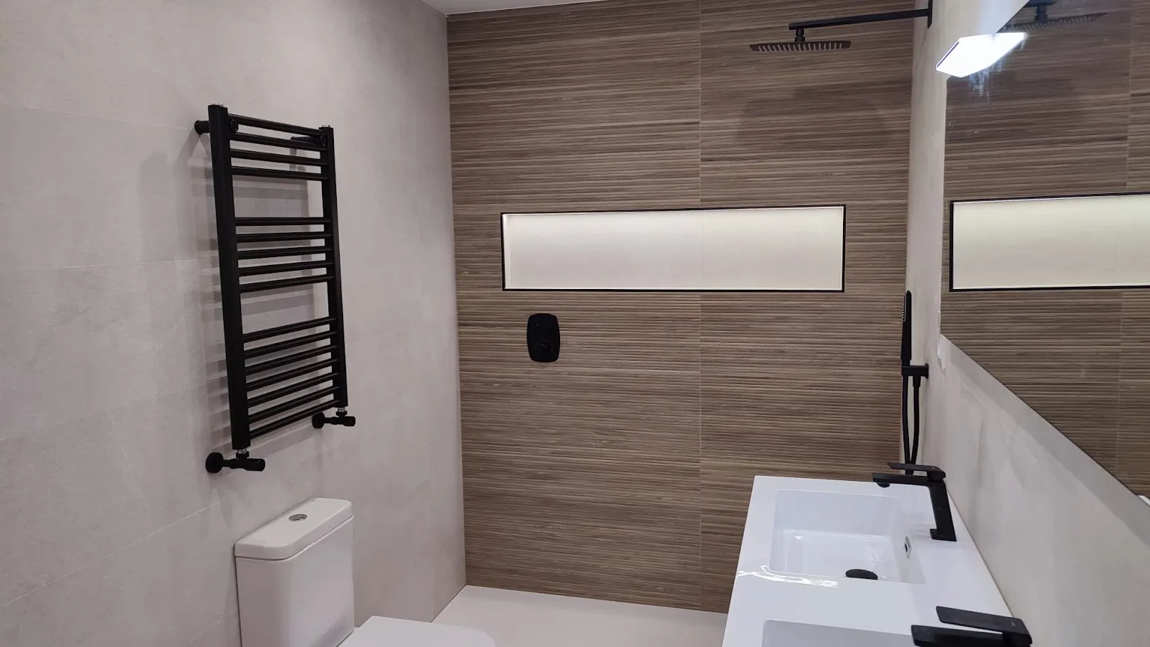 Baño con pared revestida en efecto madera y hornacina iluminada
