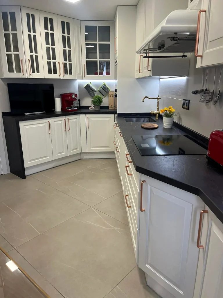Cocina blanca de estilo clásico con encimera negra, en la calle Hermanos Pinzón (Móstoles)