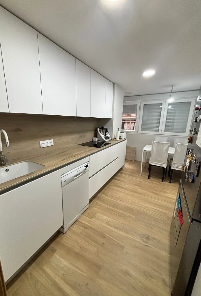 Cocina en paralelo con muebles blancos sin tirador y encimera en tono madera, en la calle Libertad (Móstoles)