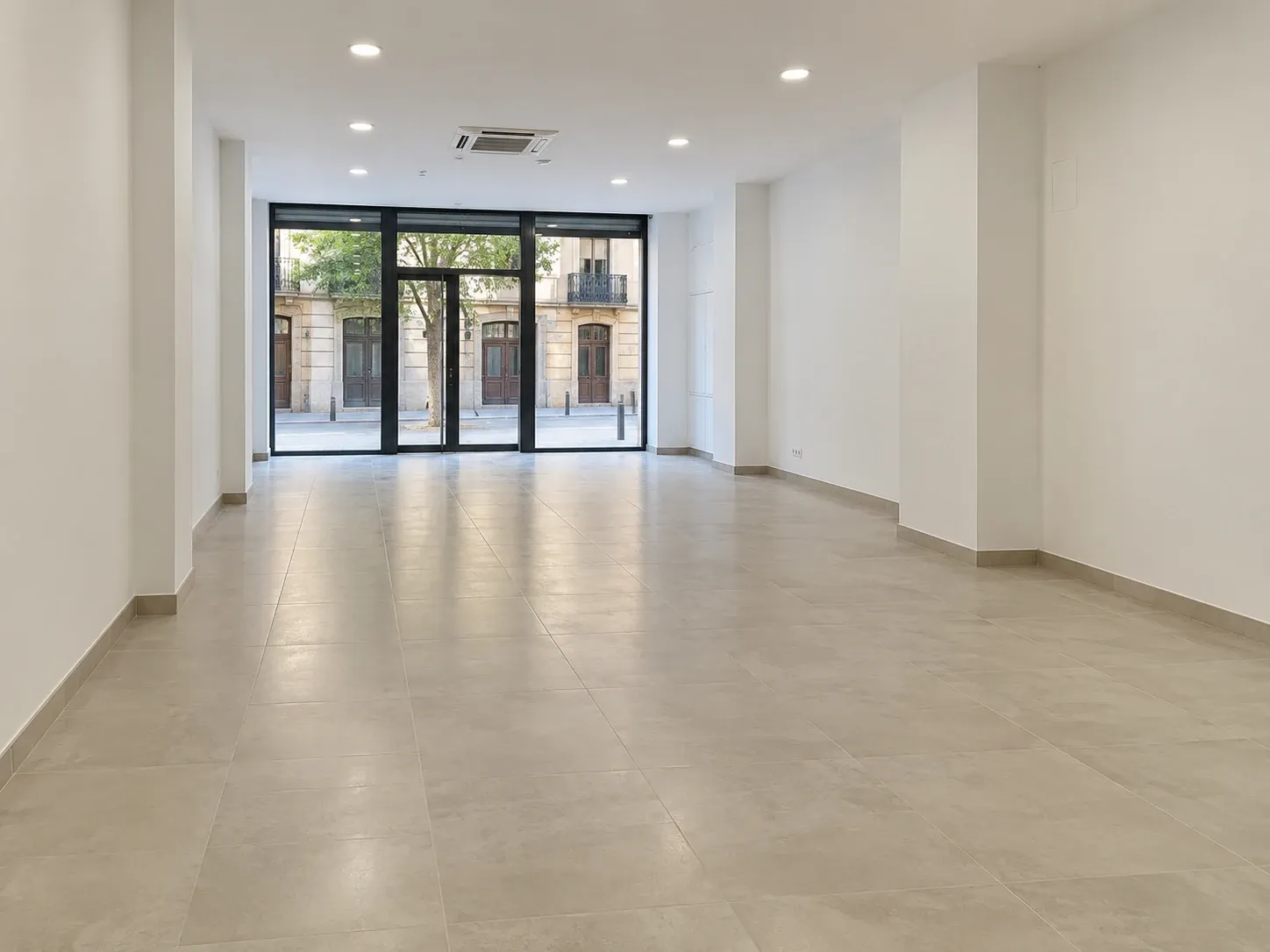 Local comercial reformado con escaparate de cristal, suelo porcelánico y techo con iluminación empotrada y climatización