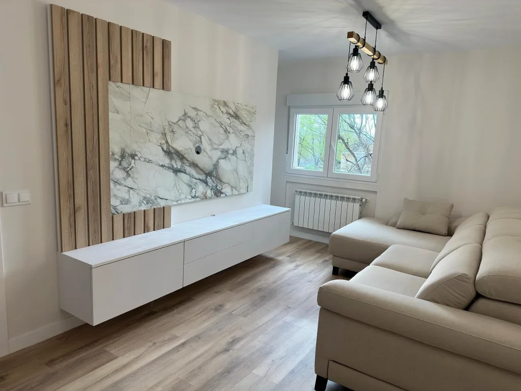 Salón reformado en la calle Pintor Velázquez de Móstoles con suelo de tarima, panel efecto mármol y sofá chaise longue